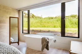 A freestanding bath sits in the master bedroom window