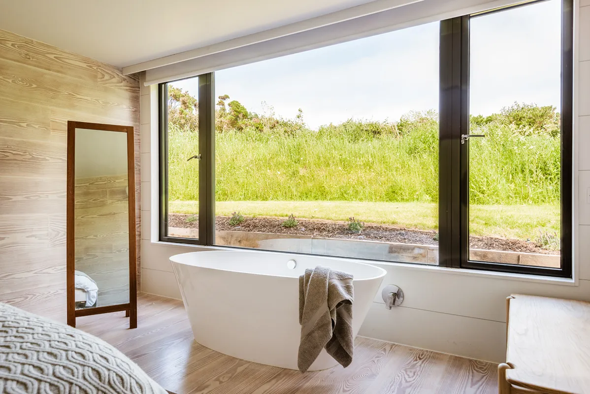 A freestanding bath sits in the master bedroom window
