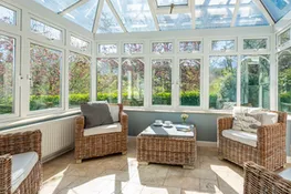 The sun room surrounded by the pretty lawned garden