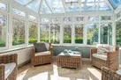 The sun room surrounded by the pretty lawned garden